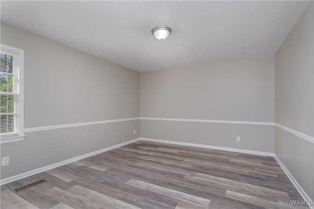 unfurnished room featuring hardwood / wood-style flooring and a textured ceiling