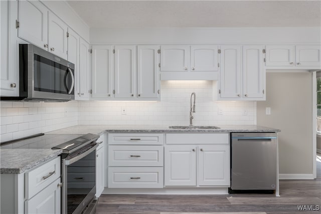 kitchen featuring appliances with stainless steel finishes, white cabinetry, sink, dark hardwood / wood-style flooring, and light stone counters