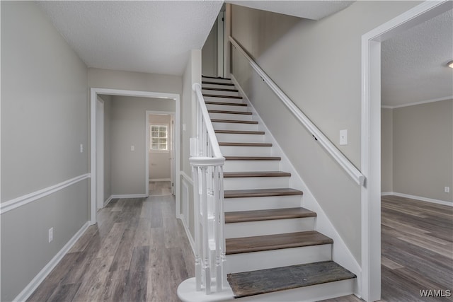 stairs with hardwood / wood-style flooring and a textured ceiling