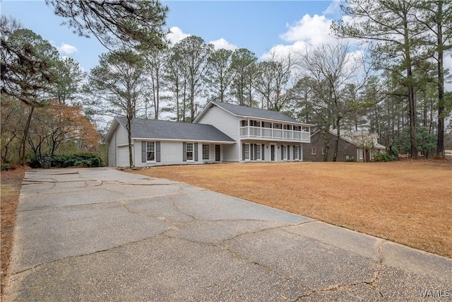 view of front of house with a balcony, a garage, and a front yard