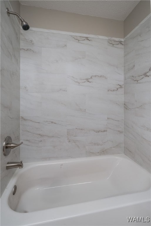 bathroom featuring tiled shower / bath and a textured ceiling