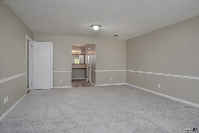 empty room with light carpet and a textured ceiling