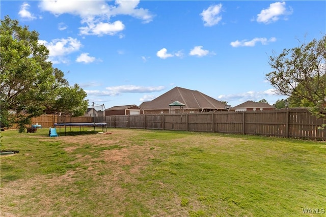 view of yard featuring a trampoline and a fenced backyard
