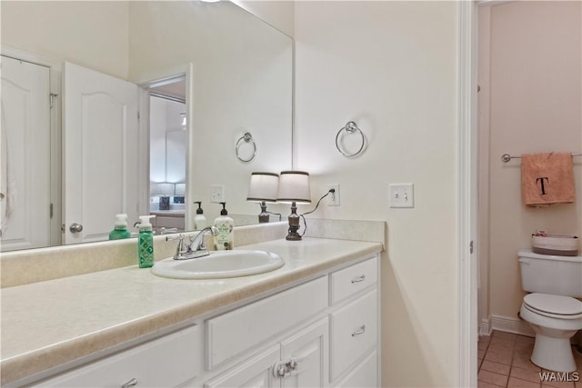 bathroom featuring baseboards, vanity, tile patterned flooring, and toilet