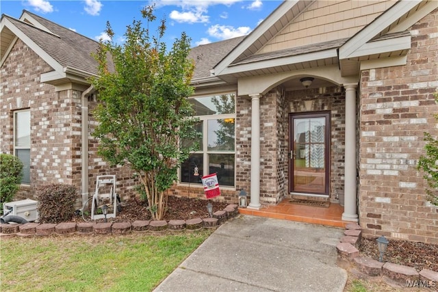 property entrance featuring brick siding and roof with shingles