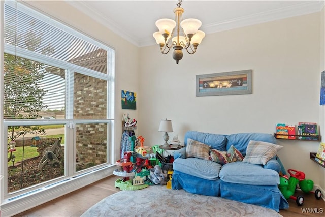 playroom with ornamental molding, a notable chandelier, wood finished floors, and a healthy amount of sunlight