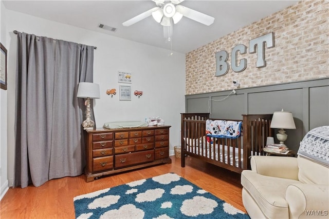 bedroom with wood finished floors, visible vents, and a ceiling fan