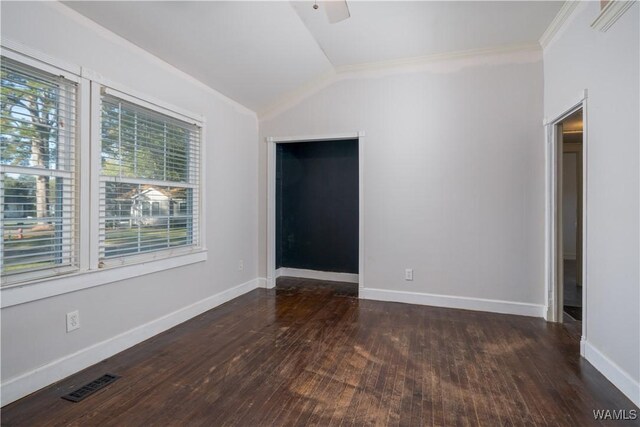 unfurnished room featuring dark hardwood / wood-style flooring, vaulted ceiling, and ornamental molding