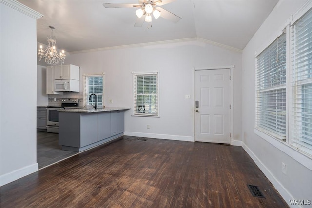 kitchen with decorative light fixtures, vaulted ceiling, kitchen peninsula, electric stove, and white cabinets