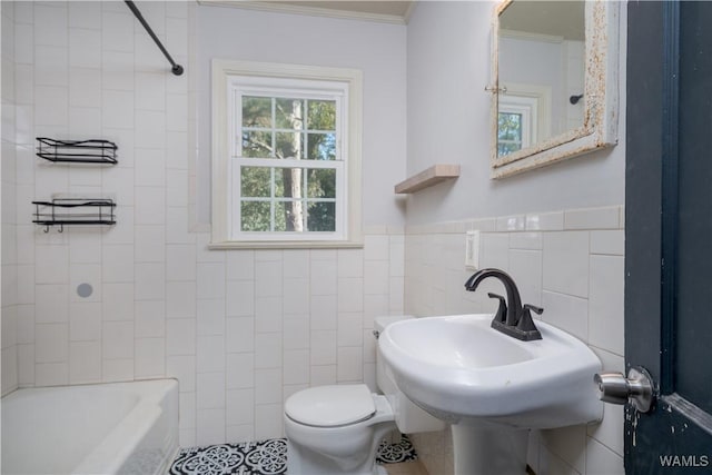 bathroom with ornamental molding, bathing tub / shower combination, tile walls, and toilet