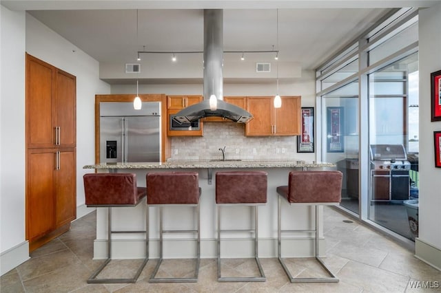 1018 Hackberry Ln Unit 404, Tuscaloosa, AL 35401 - kitchen with island range hood, tasteful backsplash, stainless steel built in refrigerator, light stone counters, and decorative light fixtures
