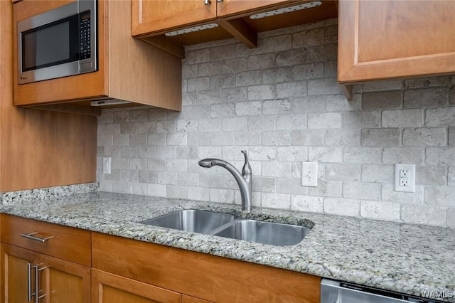 1018 Hackberry Ln Unit 404, Tuscaloosa, AL 35401 - kitchen with stainless steel microwave, backsplash, light stone counters, and brown cabinetry