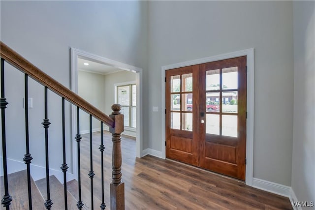 foyer entrance with french doors, a wealth of natural light, dark wood-type flooring, and a high ceiling