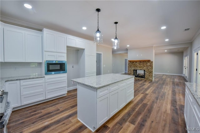 kitchen with white cabinetry, built in microwave, and crown molding