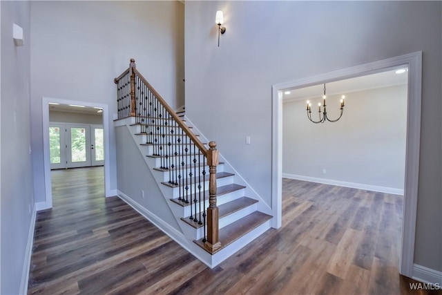 stairway with a high ceiling, a notable chandelier, and hardwood / wood-style flooring
