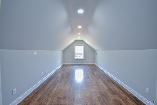bonus room with dark wood-type flooring and vaulted ceiling