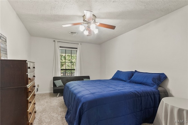 carpeted bedroom featuring ceiling fan and a textured ceiling