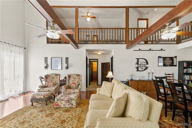 living room featuring hardwood / wood-style flooring, beam ceiling, a barn door, and a high ceiling