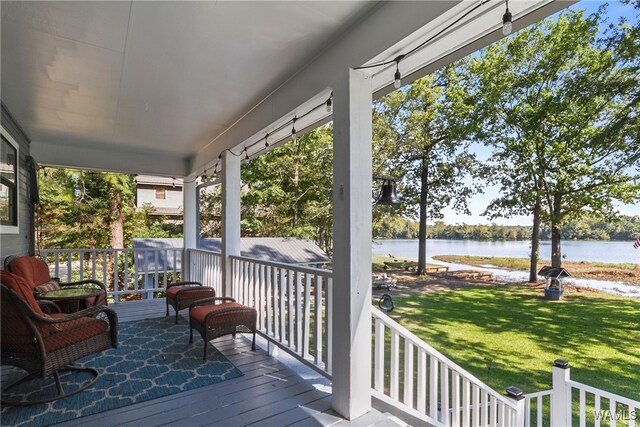 deck featuring covered porch, a water view, and a yard