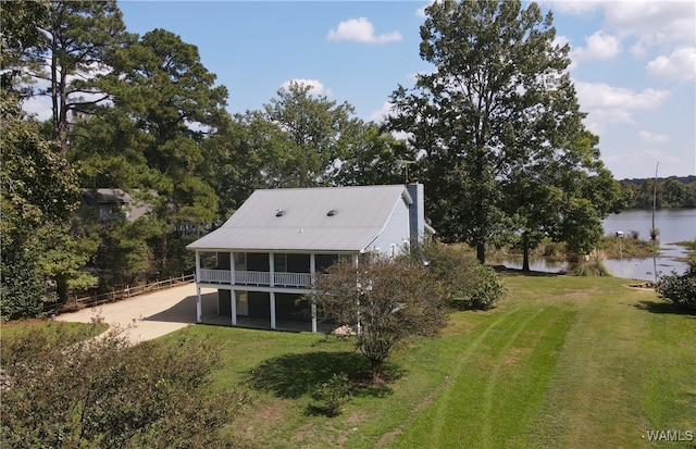 back of property with a yard and a water view