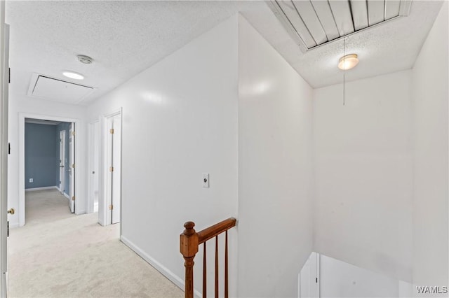 hall with light colored carpet and a textured ceiling