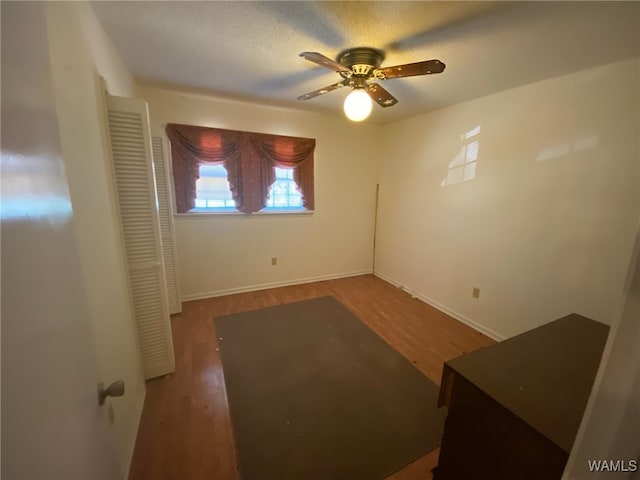 unfurnished bedroom with a ceiling fan, wood finished floors, and baseboards