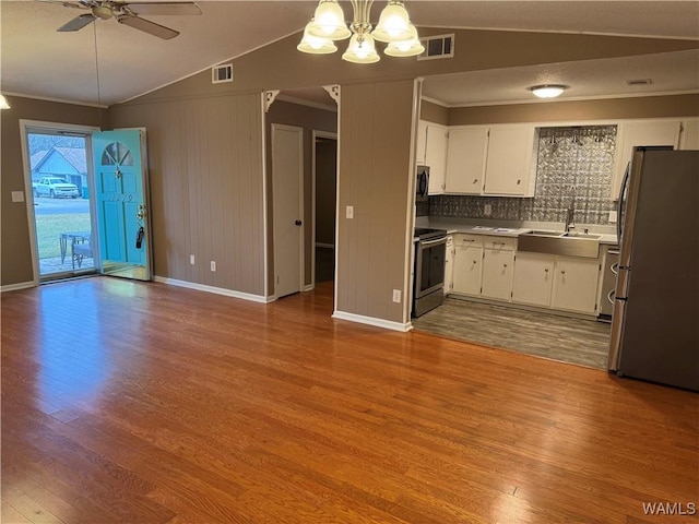 kitchen featuring white cabinetry, lofted ceiling, sink, ornamental molding, and stainless steel appliances