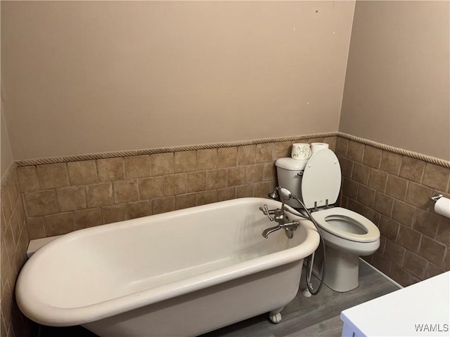 bathroom featuring tile walls, a tub to relax in, wood-type flooring, and toilet