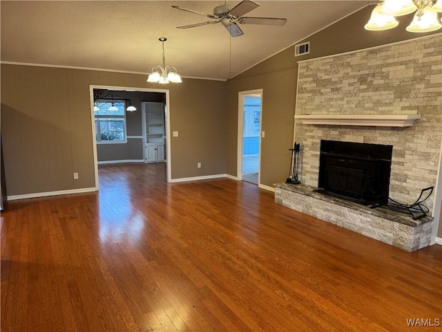 unfurnished living room with lofted ceiling, crown molding, a stone fireplace, wood-type flooring, and ceiling fan with notable chandelier