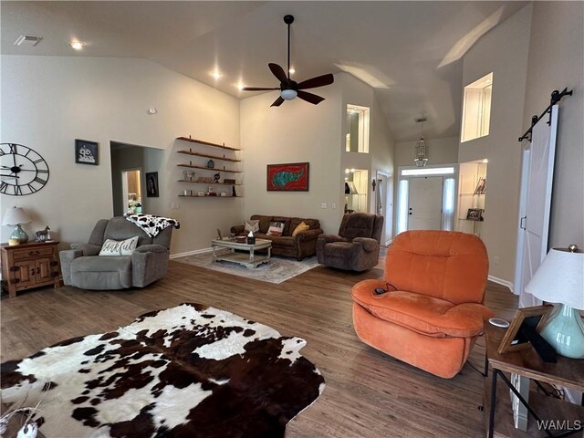 living area featuring high vaulted ceiling, dark wood-type flooring, visible vents, and a barn door