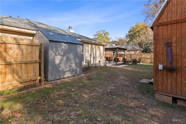 view of yard featuring a storage shed, fence, and an outdoor structure