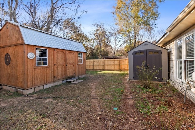 view of yard with a shed, fence, and an outbuilding