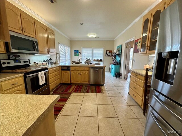 kitchen featuring light countertops, appliances with stainless steel finishes, glass insert cabinets, light tile patterned flooring, and a sink