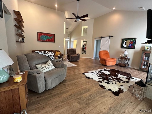 living room featuring high vaulted ceiling, a barn door, wood finished floors, visible vents, and a ceiling fan