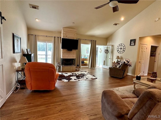 living area with dark wood-style floors, a fireplace, visible vents, and a ceiling fan