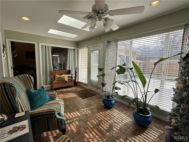 sunroom / solarium featuring a ceiling fan and a skylight