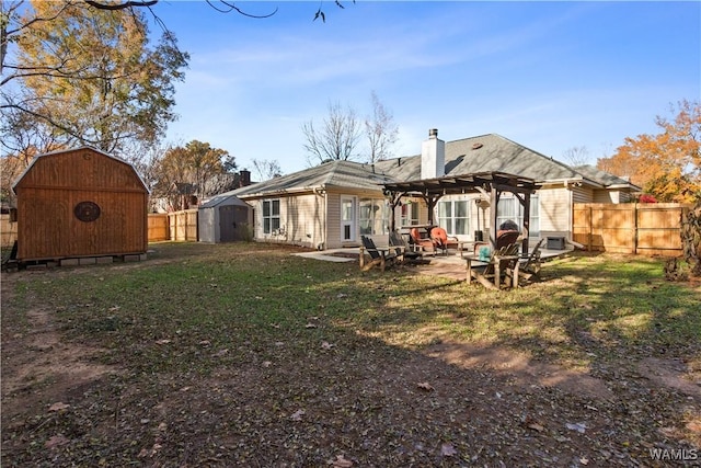 back of house with a chimney, an outbuilding, a storage unit, fence, and a pergola