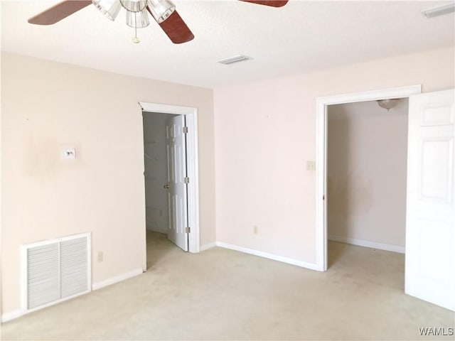 interior space with light carpet, a spacious closet, and ceiling fan