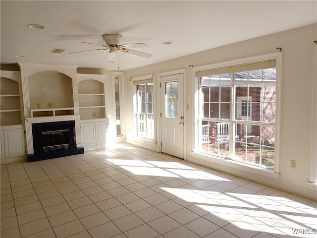 unfurnished living room with ceiling fan, light tile patterned flooring, and built in shelves