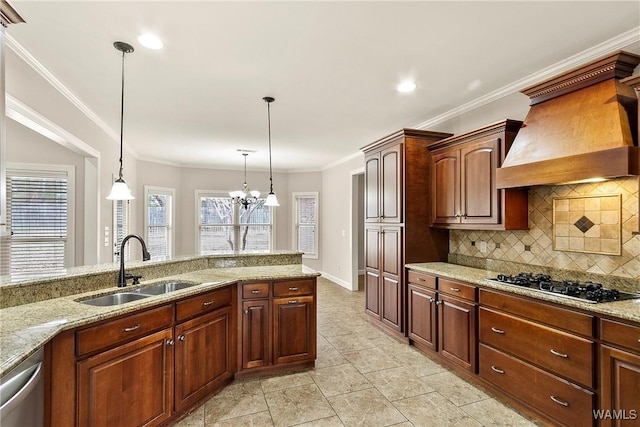 kitchen featuring sink, custom exhaust hood, light stone counters, appliances with stainless steel finishes, and pendant lighting