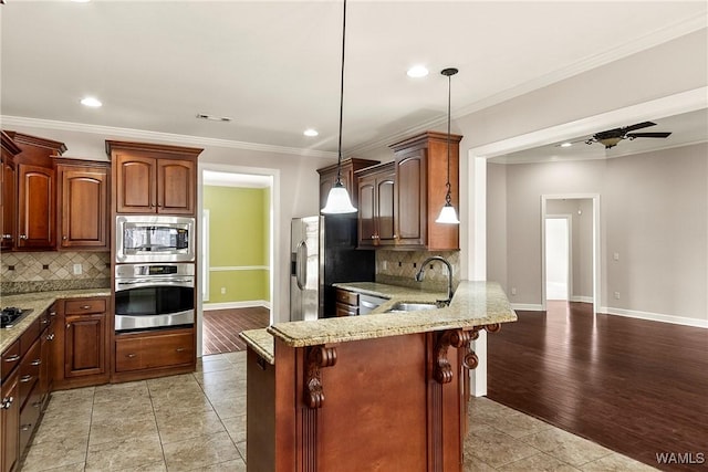 kitchen with sink, a kitchen breakfast bar, hanging light fixtures, kitchen peninsula, and stainless steel appliances