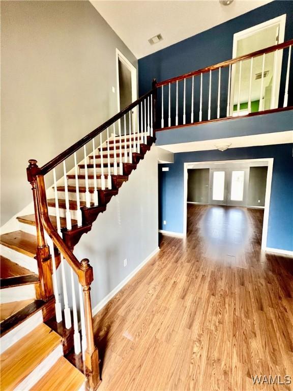 staircase featuring wood-type flooring and a towering ceiling