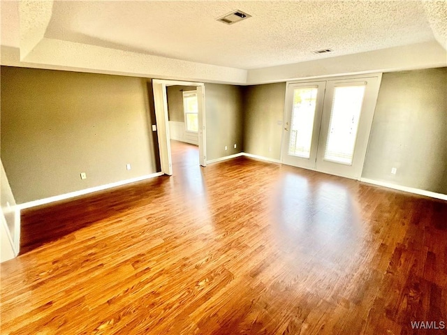 empty room with wood-type flooring and a textured ceiling