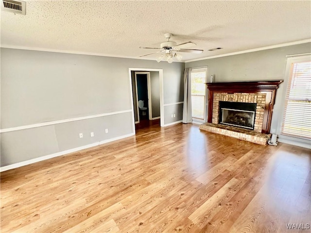 unfurnished living room featuring plenty of natural light, ornamental molding, and a brick fireplace