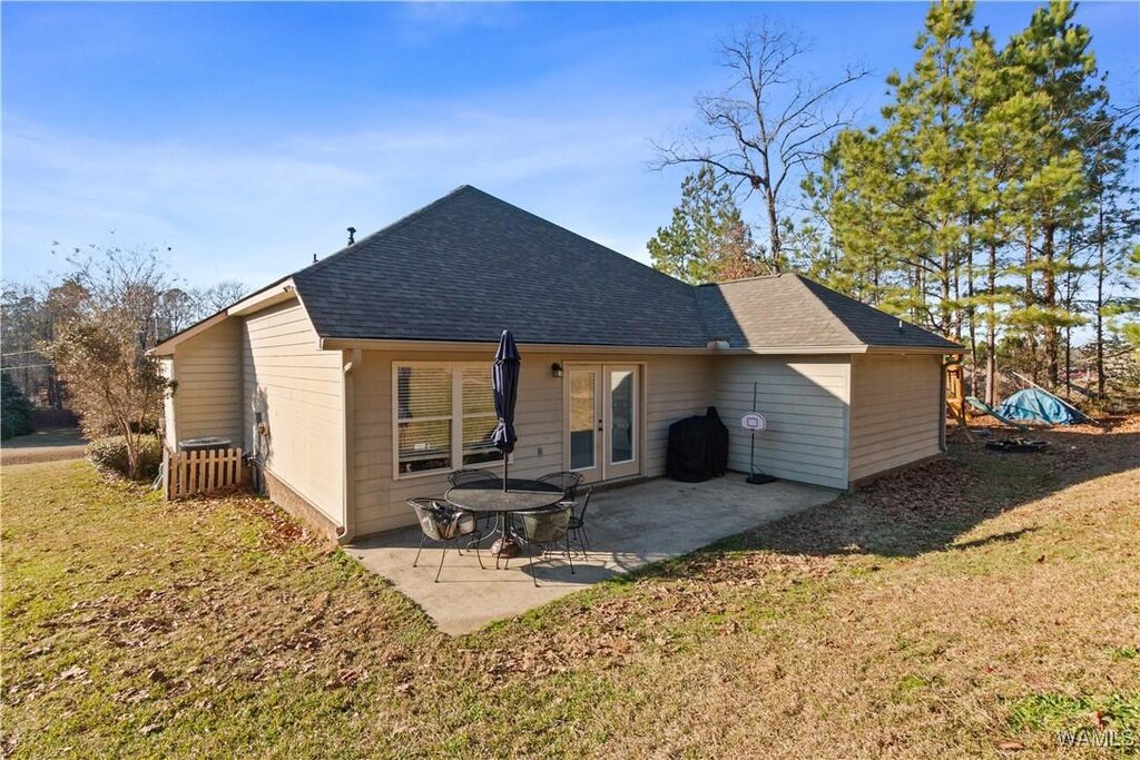 rear view of house with a yard, a patio, french doors, and roof with shingles