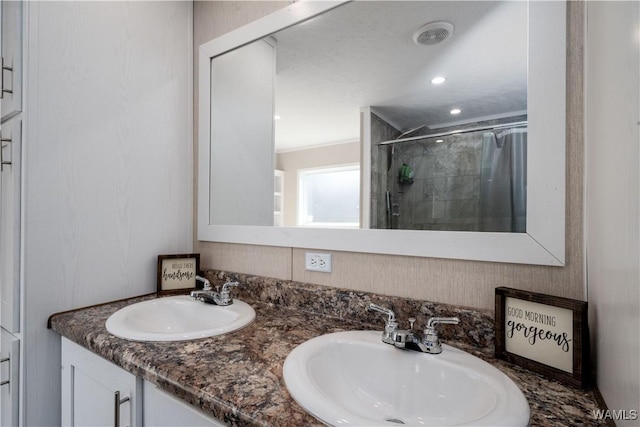 bathroom featuring double vanity, a stall shower, and a sink