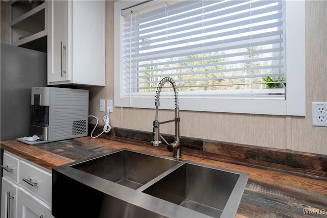 kitchen featuring white cabinetry, wooden counters, and a sink