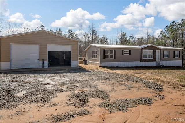 manufactured / mobile home with entry steps, an outdoor structure, a garage, and central AC