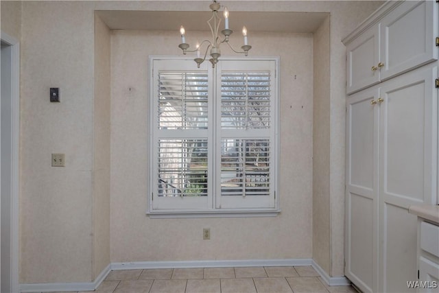 unfurnished dining area with light tile patterned floors, baseboards, a chandelier, and wallpapered walls