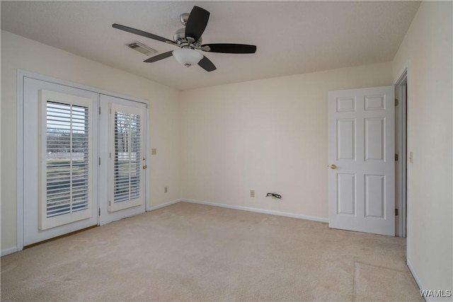 empty room featuring light carpet, visible vents, a ceiling fan, and baseboards